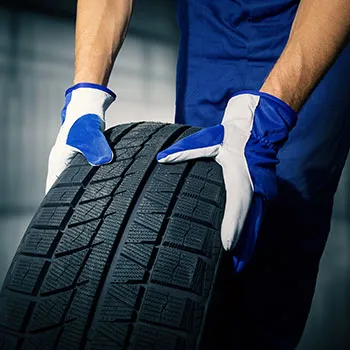 Mechanic handling car tire with gloves
